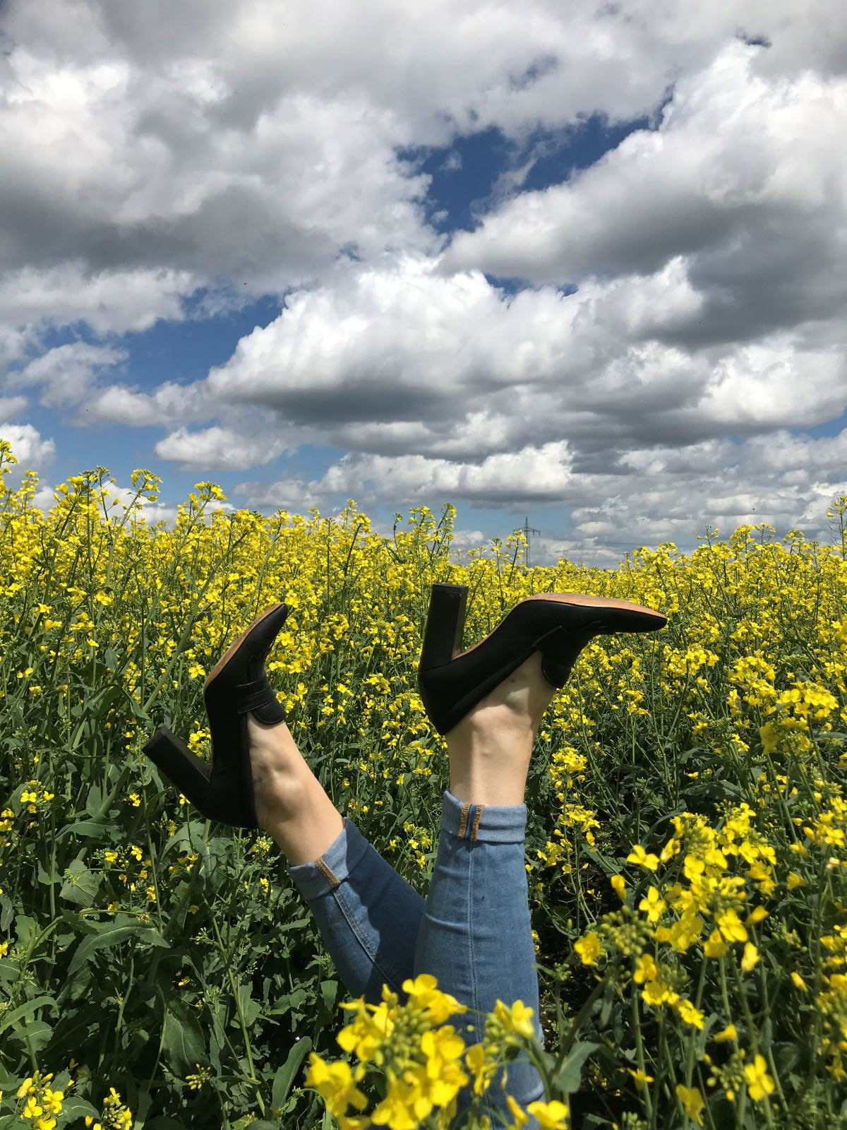Damenschuh MaYa schwarz  im Rapsfeld; Sohle in Himmel zeigend